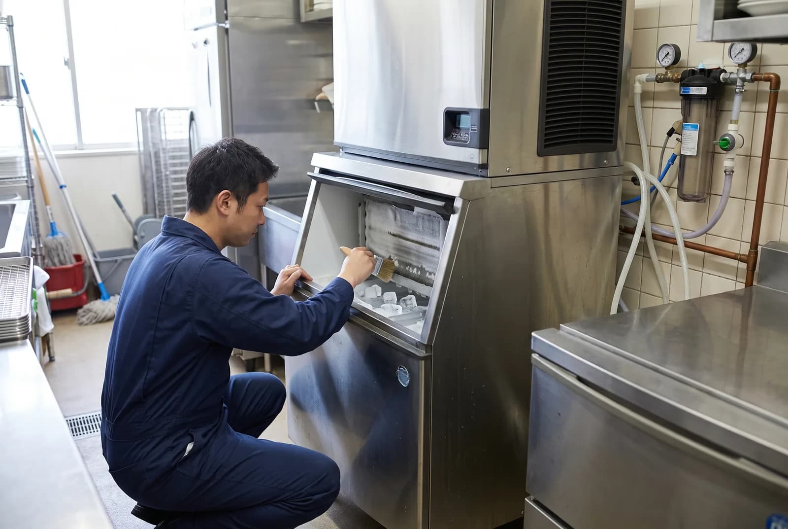 Refrigeration technician cleaning and sanitizing a commercial ice machine in a Vancouver restaurant kitchen